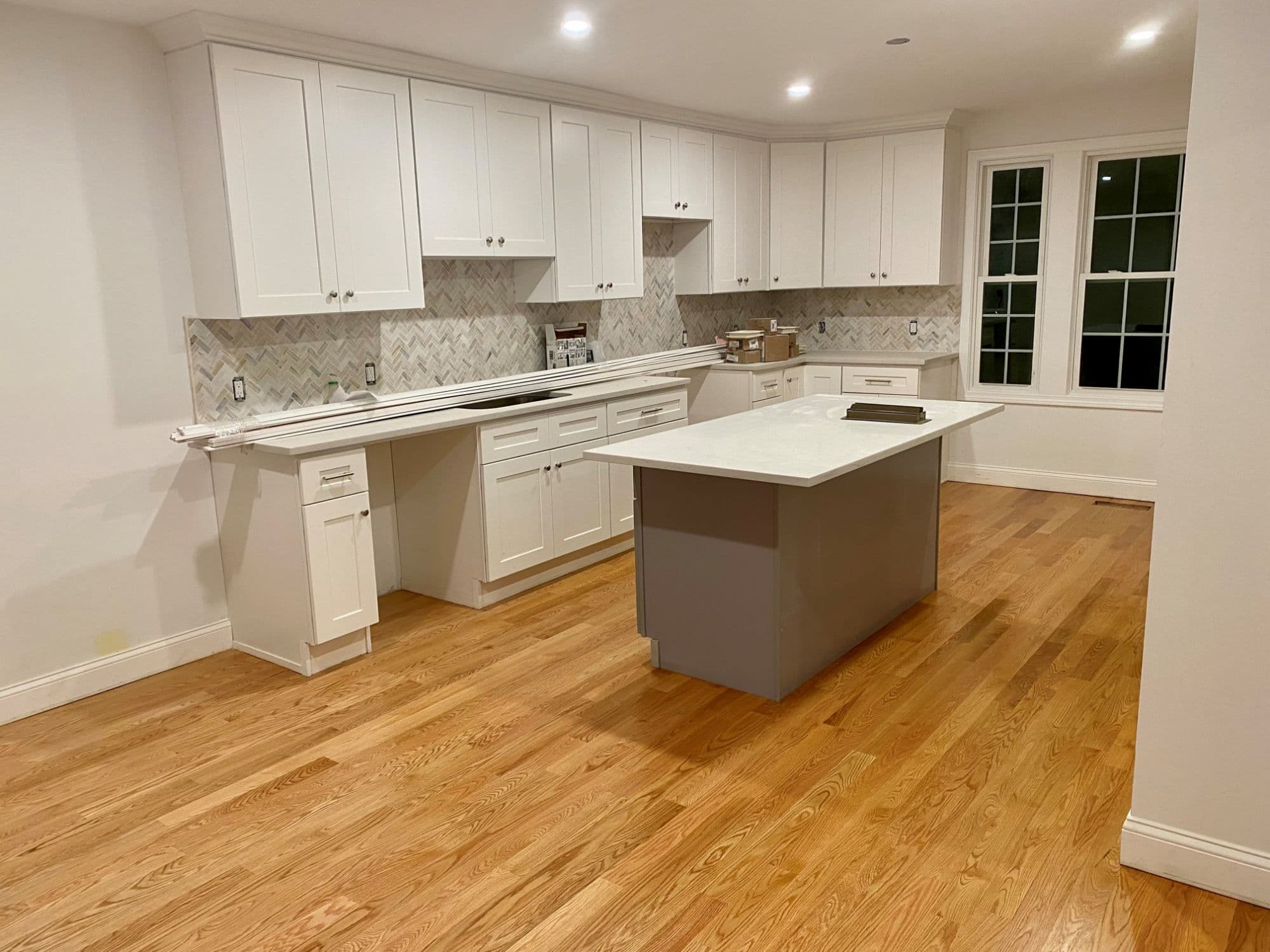 Completed kitchen remodel in Milford CT with white shaker cabinets, quartz countertops, and herringbone marble backsplash by PRC Builders